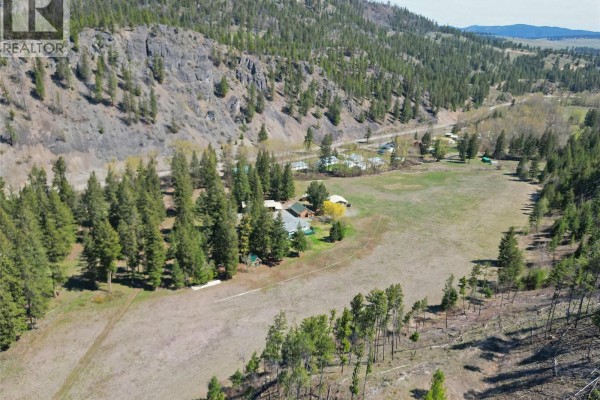 Close-up aerial view of the wooden workshop and the main house with a porch and green roof. - 1094 Highway 5a, Princeton
