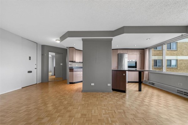 Living room and kitchen with hardwood floors, island, and large window. - 10h 300 Roslyn Road, Winnipeg