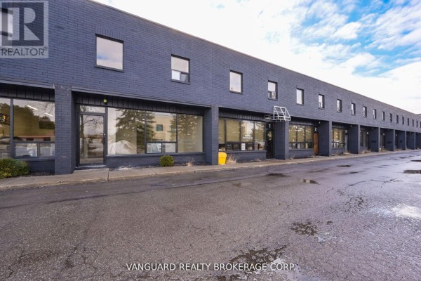 View of the exterior of a long, dark grey commercial building with multiple windows and doors. - 10r-10f - 11 Holland Drive, Caledon