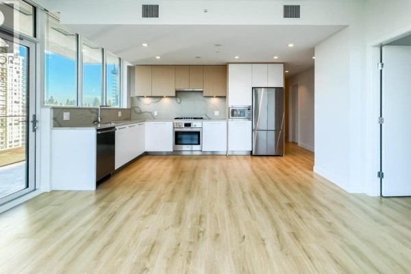 Modern kitchen with white and light wood cabinetry, stainless steel appliances, and island. - 10xx 567 Clarke Road, Coquitlam