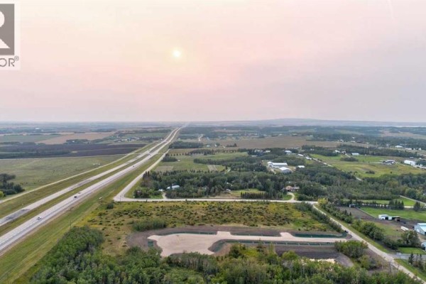 Expansive aerial view of undeveloped land adjacent to a highway with distant countryside. - 11, 701413 Range Road 72, Rural Grande Prairie No  1, County Of