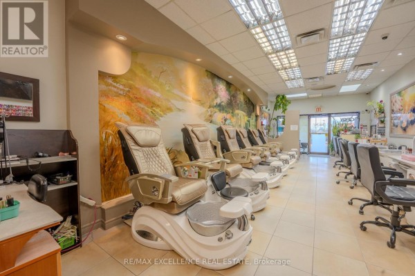 Side view of pedicure chairs and manicure stations with a decorative mural on the wall. - 11 - 1 Steeles Avenue, Brampton