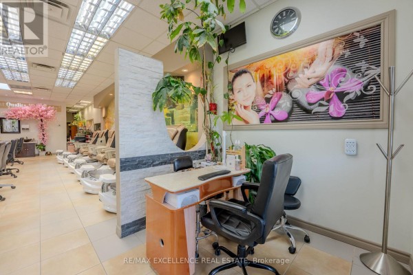 A manicure desk with a chair sits near a potted plant and decorative wall art. - 11 - 1 Steeles Avenue, Brampton