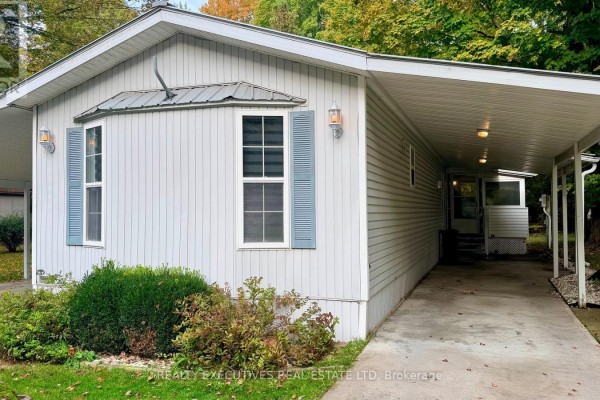 Close-up of the front of a mobile home with light-colored siding and blue shutters. - 11 - 10146 County 43 Road, North Dundas