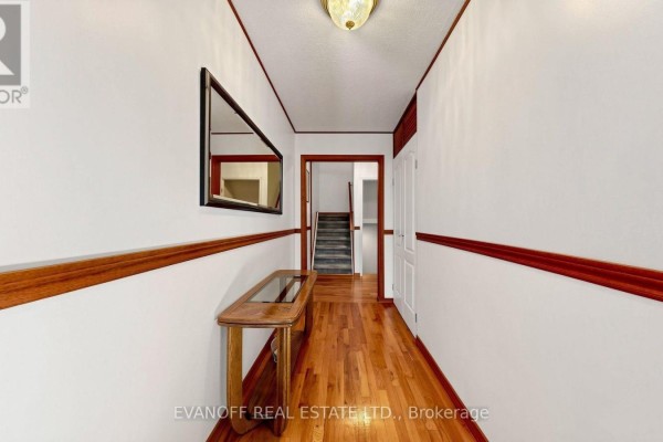 Interior hallway with polished hardwood floors, white walls, and a wooden console table. - 11 - 117 Burrows Hall Boulevard, Toronto