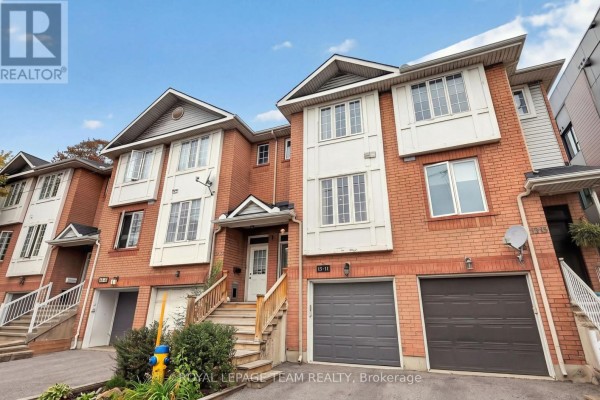Front exterior of attached brick townhouses showing entrances and garages. - 11 - 13 Robinson Avenue, Ottawa