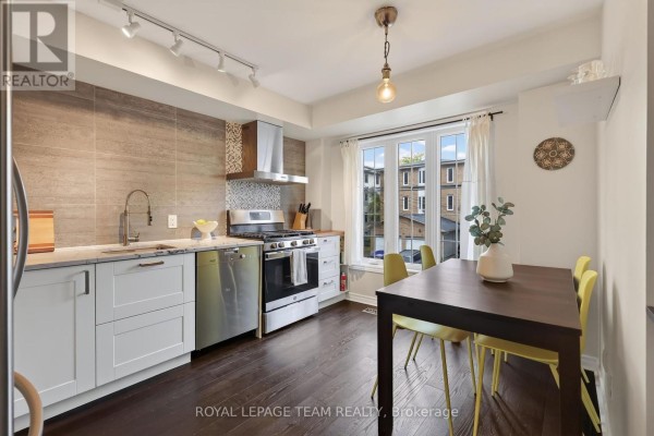 Kitchen with white cabinets, stainless steel appliances, and dark wood floors. - 11 - 13 Robinson Avenue, Ottawa