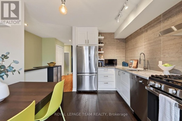 Kitchen with stainless steel refrigerator, white cabinets, and tile backsplash. - 11 - 13 Robinson Avenue, Ottawa