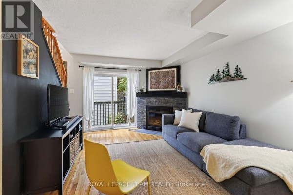 Living room with a grey sectional sofa, fireplace, and wood floors. - 11 - 13 Robinson Avenue, Ottawa