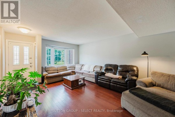 Living room with bay window, sectional sofa, dark wood floor, and entryway with glass door. - 11 - 151 Martinet Avenue, London East