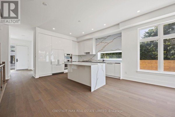 Spacious kitchen and living area with white cabinets, island, dark wood floors, and windows. - 11 - 20 Lou Parsons Way, Mississauga