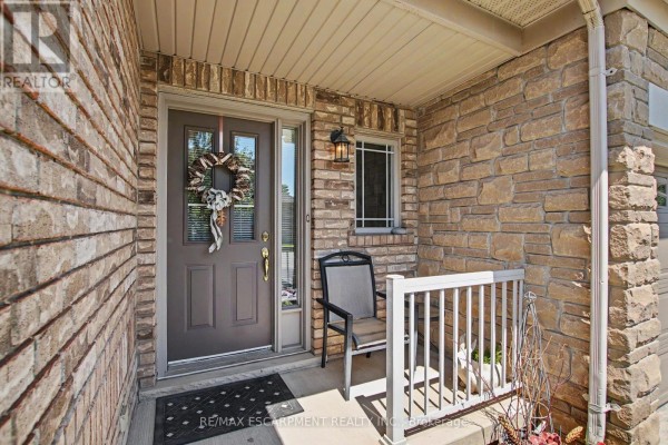 Covered front porch with a dark brown door and stone exterior. - 11 - 2169 Orchard Road, Burlington