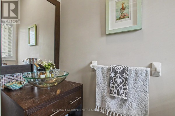 Powder room with a dark wood vanity and glass vessel sink. - 11 - 2169 Orchard Road, Burlington