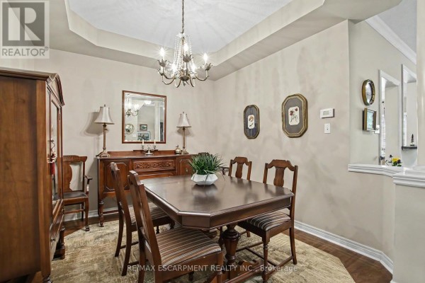 Dining room with a large wooden table, chairs, and chandelier. - 11 - 2169 Orchard Road, Burlington