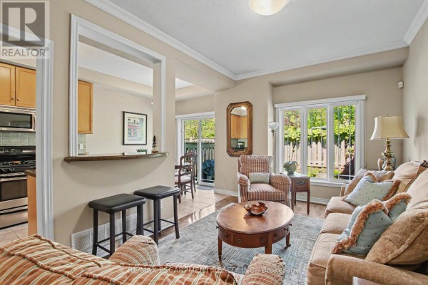 Living room with sofa, armchair, coffee table, and view of kitchen. - 11 - 2169 Orchard Road, Burlington
