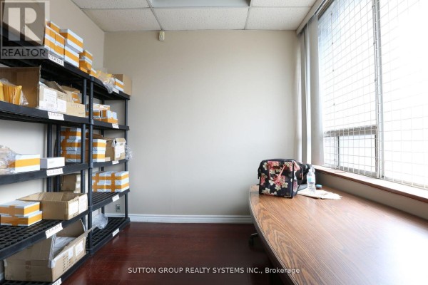 Office space with a wooden desk, chair, shelving unit with boxes, and large window. - 11 - 2266 Drew Road, Mississauga