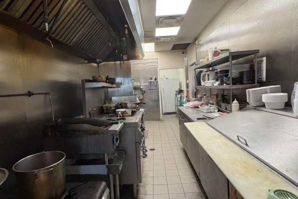 Commercial kitchen with stainless steel surfaces, professional gas range, and shelving with cookware. - 11 - 511 Maple Grove Drive, Oakville