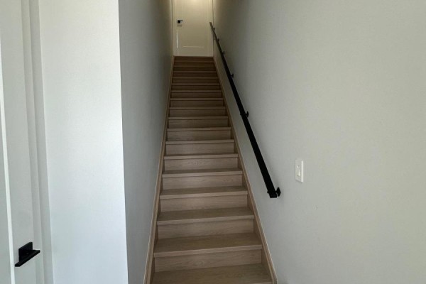 Interior staircase with light wood treads and a black handrail. - 11 - 59 Charles Street, Newmarket