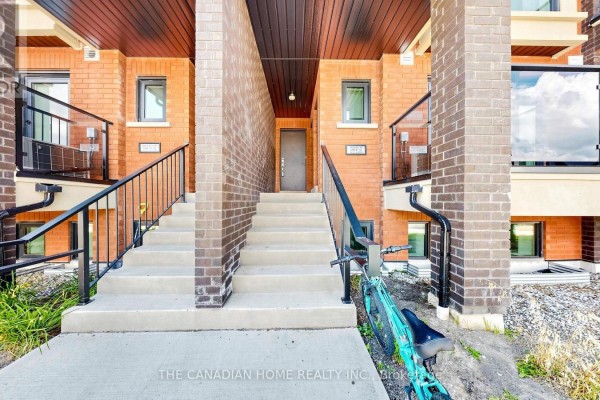 Staircase leading up to the front entrance of a brick townhouse with glass railings. - 11 - 65 Romilly Avenue, Brampton