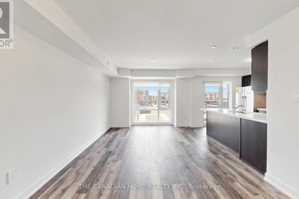 Open concept living area with white walls, dark wood floors, and a kitchen island. - 11 - 65 Romilly Avenue, Brampton