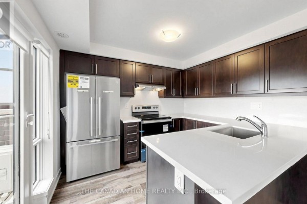 Modern kitchen with dark wood cabinets, stainless steel appliances, and white countertops. - 11 - 65 Romilly Avenue, Brampton