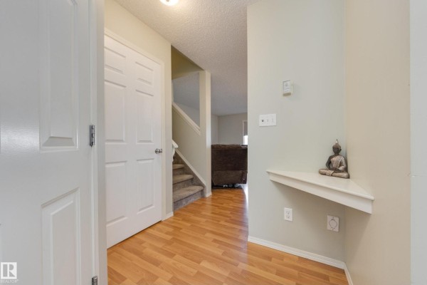 Interior foyer with light wood laminate flooring, white doors, and stairs leading up. - #11 115 Chestermere Dr, Sherwood Park