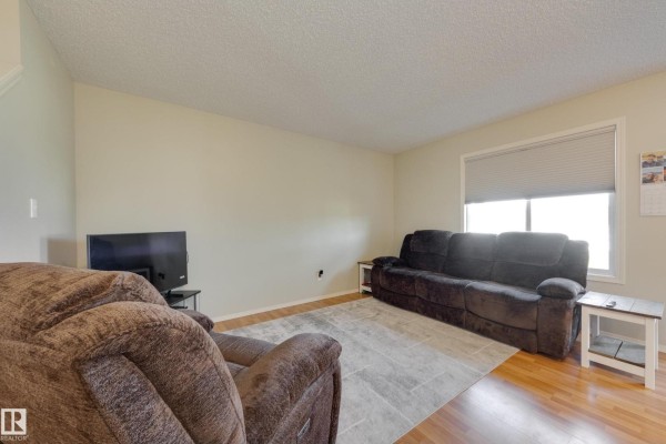 Living room with two recliners, a sofa, a television, and a large window. - #11 115 Chestermere Dr, Sherwood Park