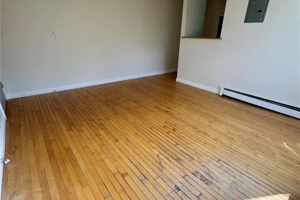 Living room with hardwood floors, beige walls, and large window with outdoor view. - 11 2320 13th Avenue, Regina