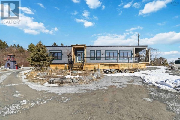 Front view of the house with a gravel driveway and surrounding snow. - 11 693 Masons Beach Road, First South
