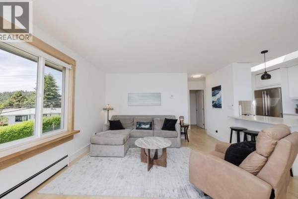 Dining area with wooden table, chairs, mirror, and window view. - 11 694 School Road, Gibsons