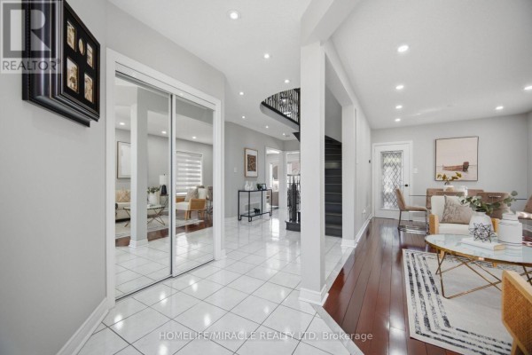 Living room with white sofa, armchair, coffee table, and arched entryway view. - 11 Barleyfield Road, Brampton