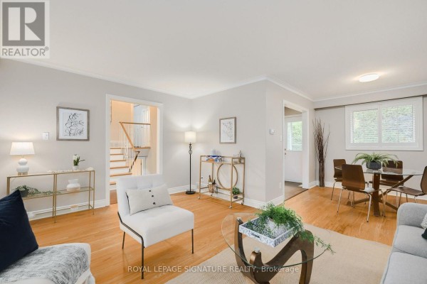 Living room with hardwood floors, a dining area, and stairs leading to the second floor. - 11 Bellbury Crescent, Toronto
