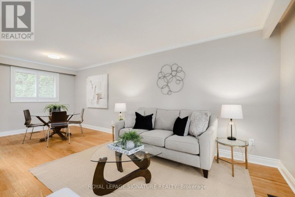 Living room featuring a sofa, coffee table, and dining area with wood-frame chairs. - 11 Bellbury Crescent, Toronto