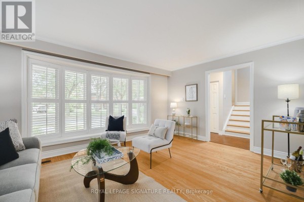 Living room interior with a sofa, chairs, dining area, and a view of the staircase. - 11 Bellbury Crescent, Toronto