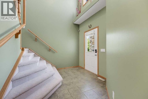 Interior entryway with a green accent wall and light grey tiled floor. - 11 Bow Ridge Link, Cochrane
