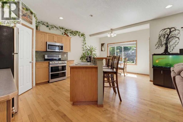 Kitchen with light wood cabinets, stainless steel appliances, and a breakfast bar. - 11 Bow Ridge Link, Cochrane