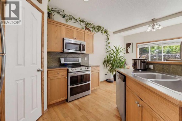 Kitchen with light wood cabinets, stainless steel appliances, and a double sink. - 11 Bow Ridge Link, Cochrane