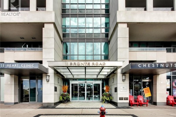 Close-up of the modern condo building entrance with automatic doors and planters. - 11 Bronte Road Unit# 306, Oakville