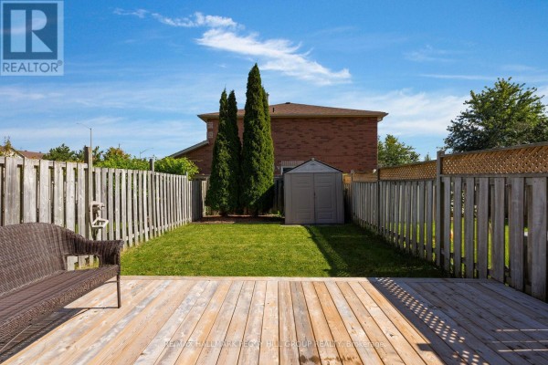 Backyard view with a wooden deck, green lawn, shed, and wooden fence. - 11 Caribou Court, Barrie