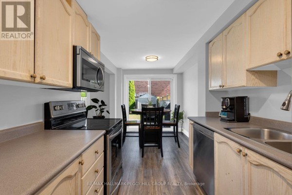 Kitchen with light wood cabinets, grey countertops, stainless steel appliances, and dining area. - 11 Caribou Court, Barrie