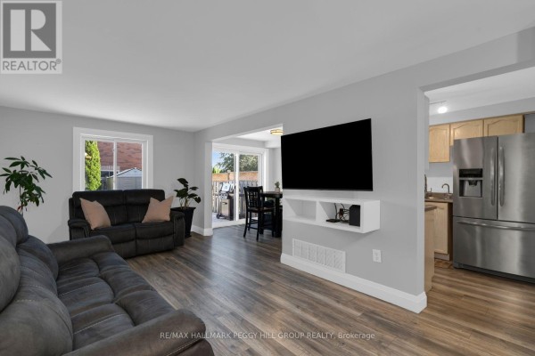 Living room with grey couches, mounted TV, and view of the dining area. - 11 Caribou Court, Barrie