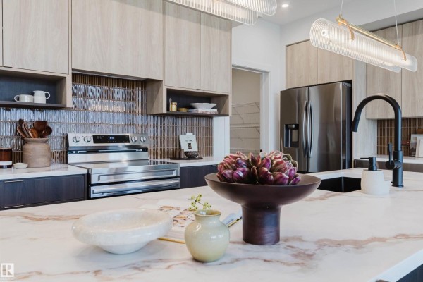 Kitchen island detail with marble countertop, decorative bowl, and black faucet. - 11 Cessy St, St  Albert