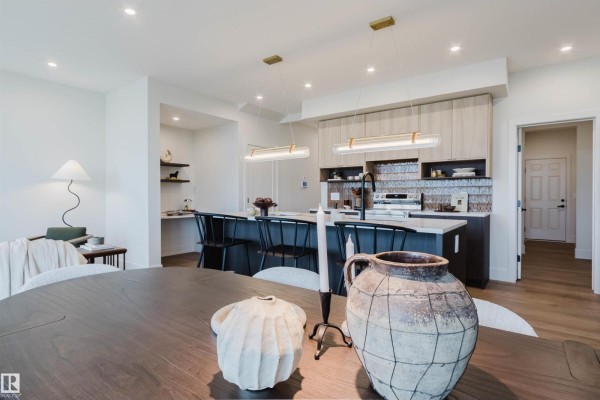Open-concept living space with dining table, kitchen island, and built-in desk area. - 11 Cessy St, St  Albert