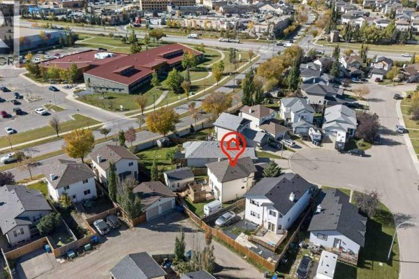 Aerial view of a residential neighborhood showing houses, streets, and a school in the distance. - 11 Cimarron Meadows, Okotoks