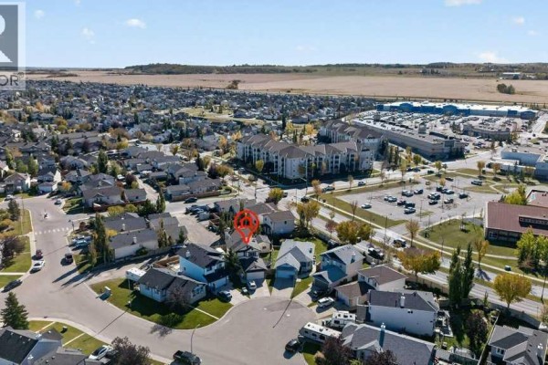 Aerial view of a suburban neighborhood with a focus on a cul-de-sac and surrounding commercial buildings. - 11 Cimarron Meadows, Okotoks