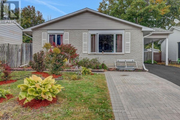 Front view of a light brick bungalow with landscaping, a paved driveway, and covered carport. - 11 Courtney Road, Ottawa