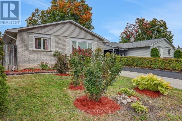 Exterior of a bungalow with a manicured front lawn, shrubs, and a paved driveway. - 11 Courtney Road, Ottawa