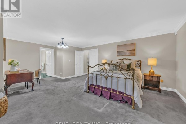 Bedroom with a large metal bed frame, grey carpet, dark wood dresser, and white doors. - 11 Cramar Crescent, Chatham Kent