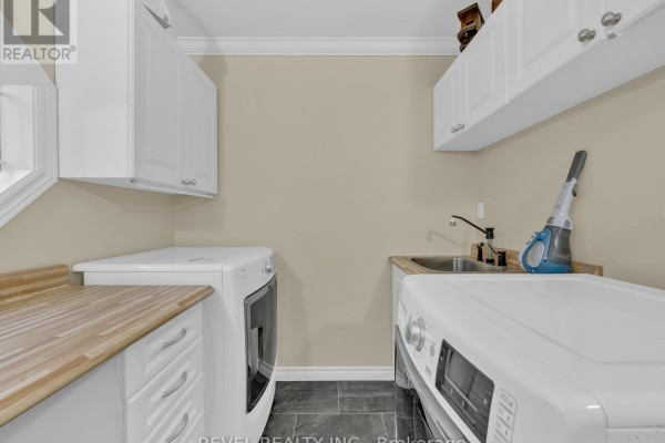 Laundry room with white cabinets, wooden countertops, a sink, a washer, and a dryer. - 11 Cramar Crescent, Chatham Kent