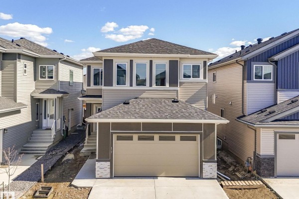 Open-concept kitchen and living area with a dark blue island and light wood cabinets. - 11 Dalquist Bay, Leduc